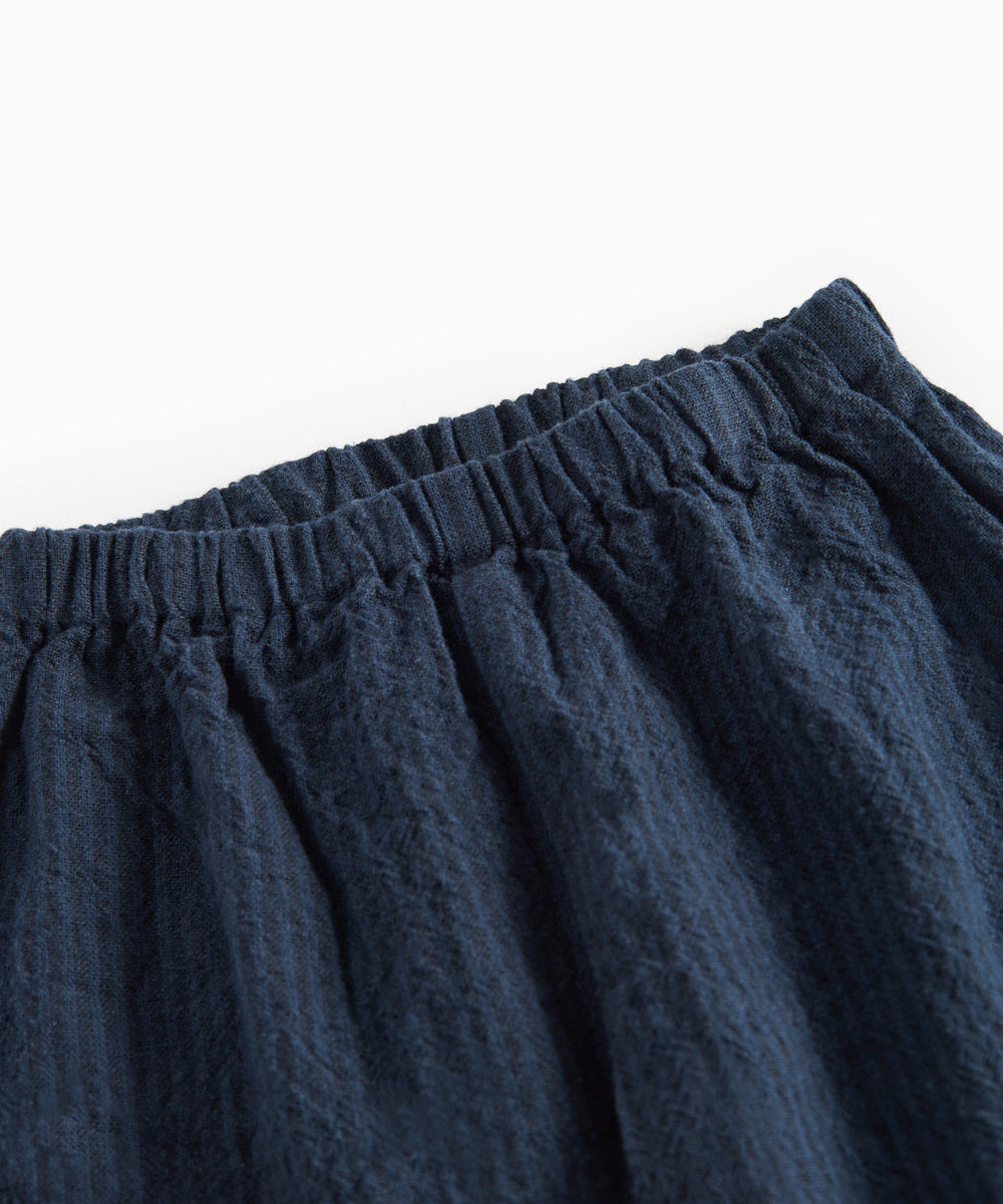 Detaljebillede af elastik i taljen på mørkeblå bukser