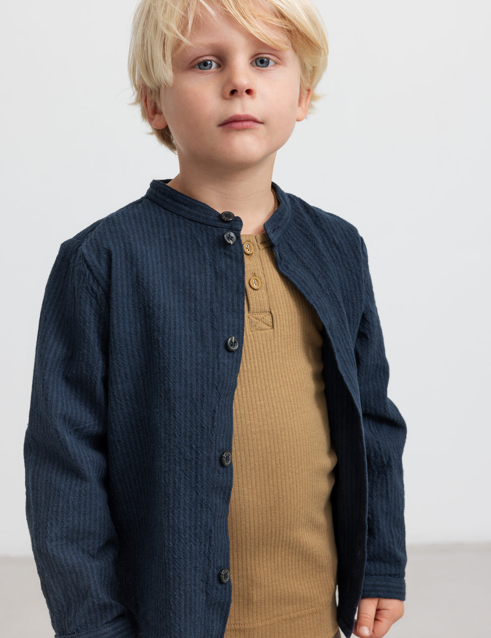 Dreng med blå jakke og brun ribbet t langærmet t-shirt