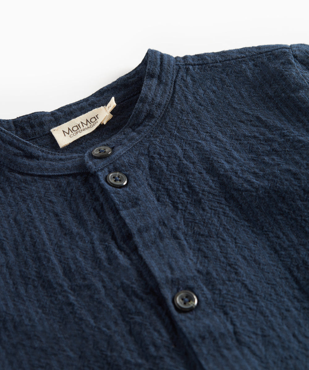 Detaljebillede af knapper og stofstruktur på mørkeblå skjorte
