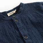 Detaljebillede af knapper og stofstruktur på mørkeblå skjorte