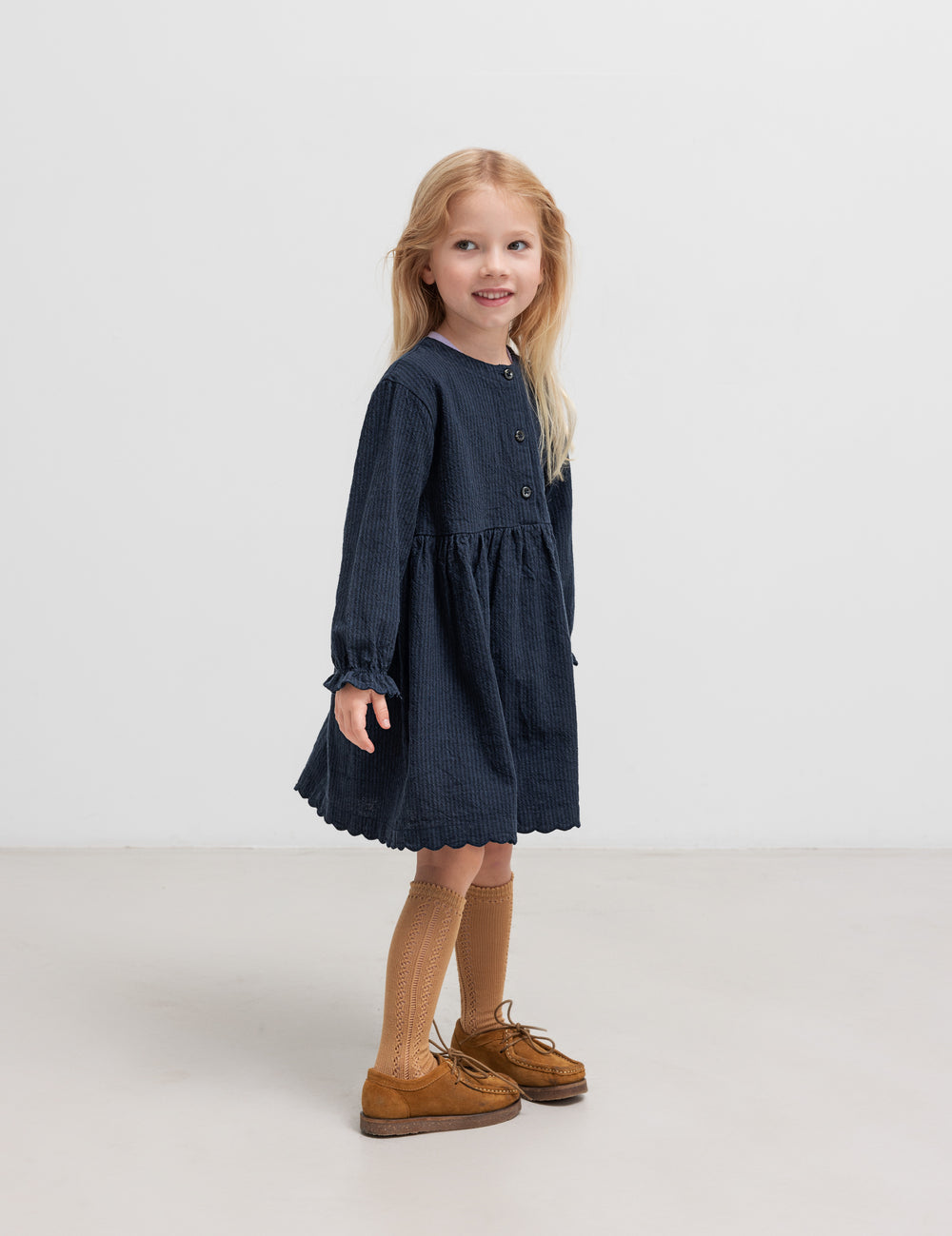 Pige iført mørkeblå kjole med rynket talje