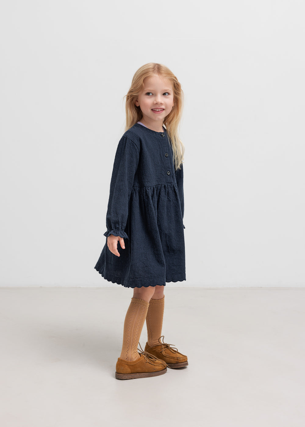 Pige iført mørkeblå kjole med rynket talje 