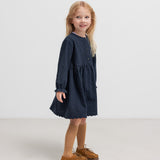 Pige iført mørkeblå kjole med rynket talje 