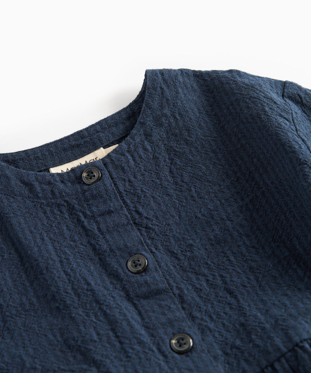 Detaljebillede af knapper og stofstruktur på mørkeblå kjole