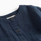 Detaljebillede af knapper og stofstruktur på mørkeblå kjole