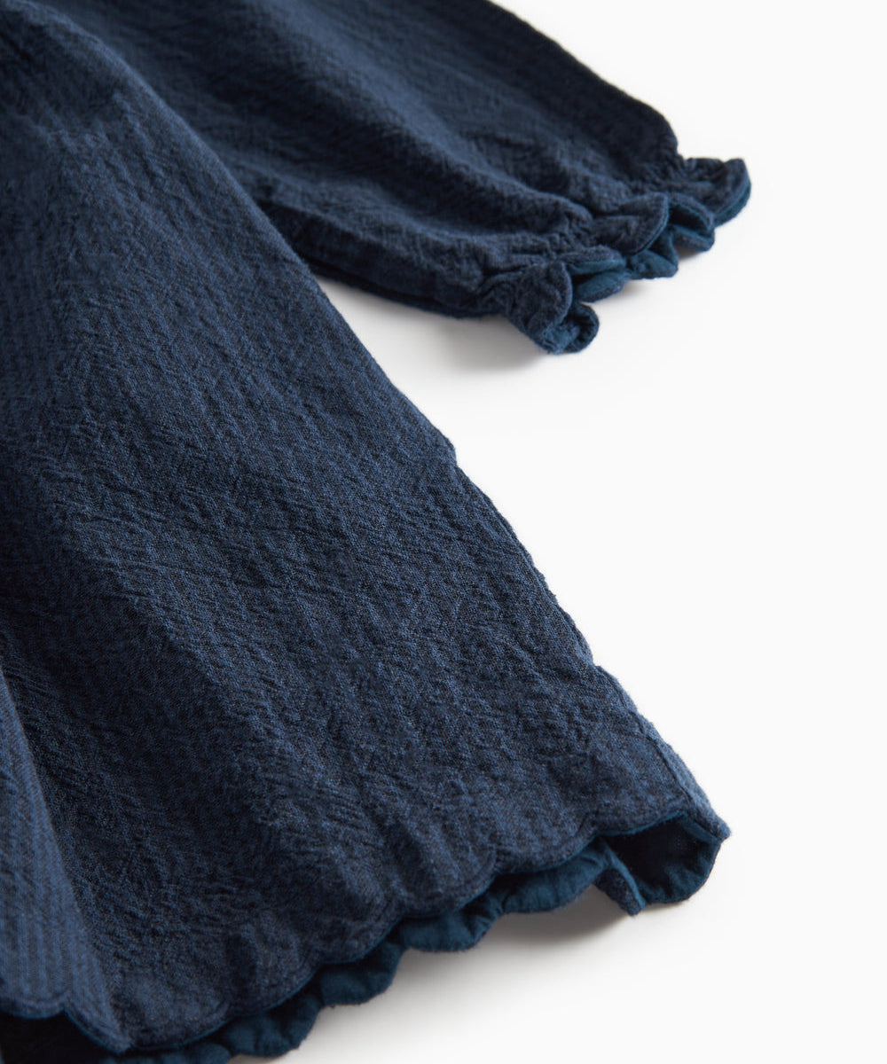 Detaljebillede af ærmekant med bølget afslutning på mørkeblå kjole