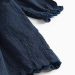 Detaljebillede af ærmekant med bølget afslutning på mørkeblå kjole