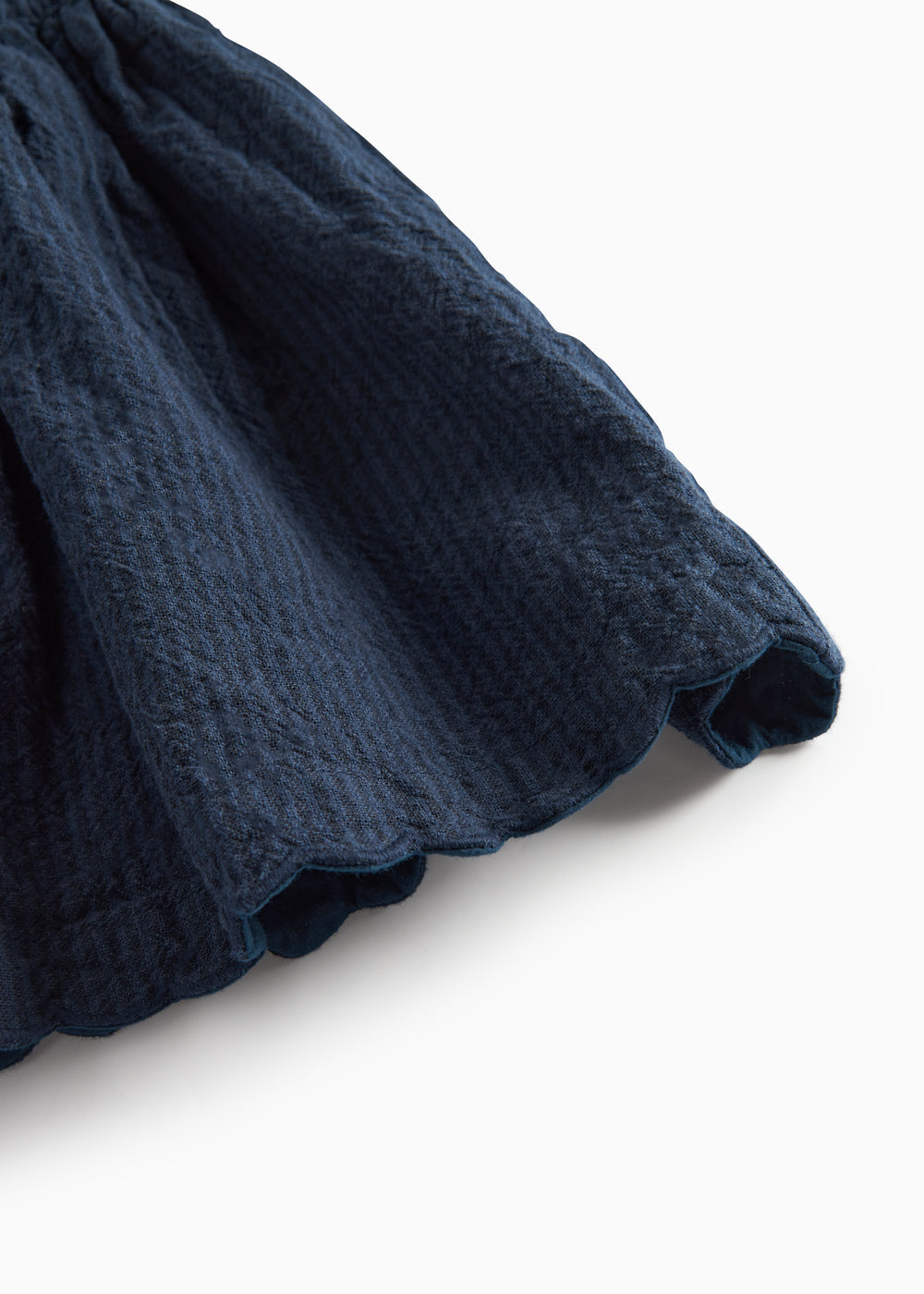 Detaljebillede af skørtets bølgede kant på mørkeblå selekjole