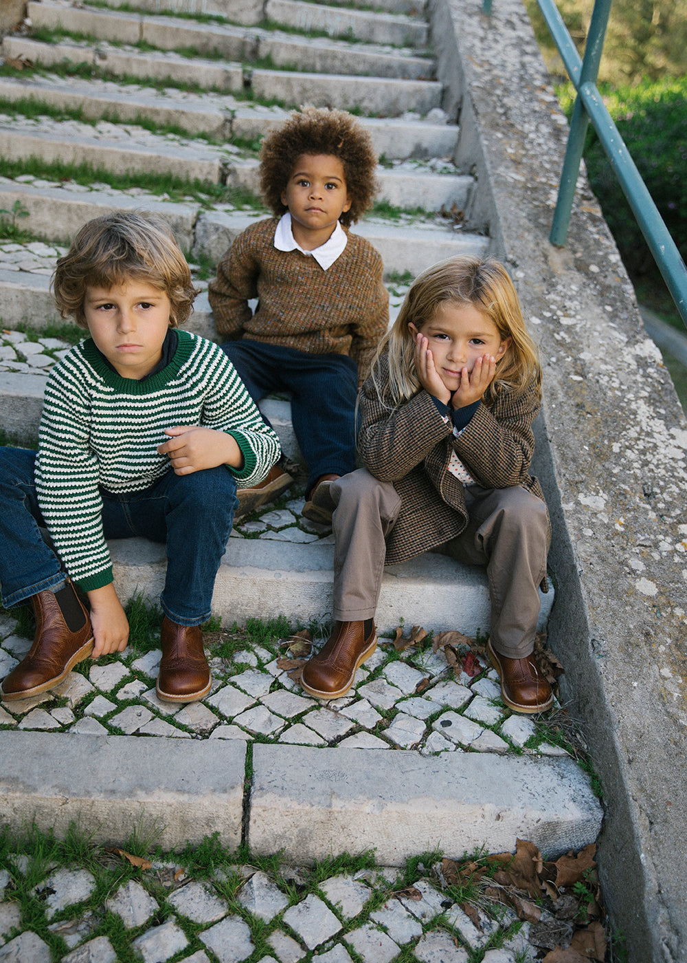 Gruppe børn sidder på trappe iført efterårsjakker og strik