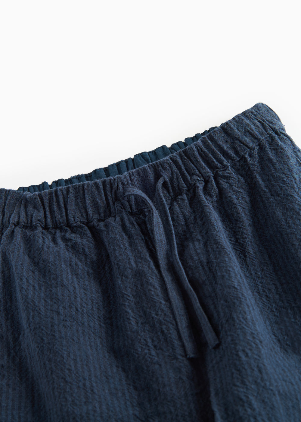 Detaljebillede af elastik i taljen på mørkeblå bukser