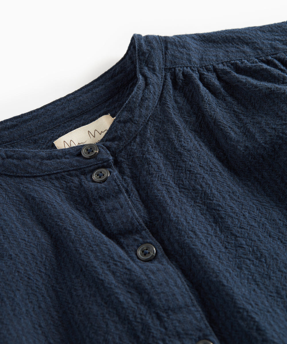 Detaljebillede af mørkeblå bluse med knapper foran