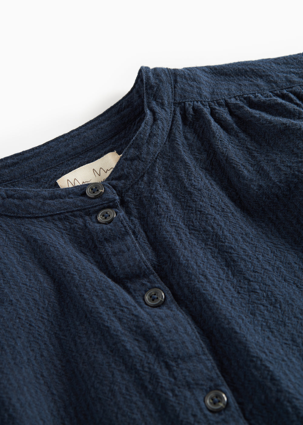 Detaljebillede af mørkeblå bluse med knapper foran