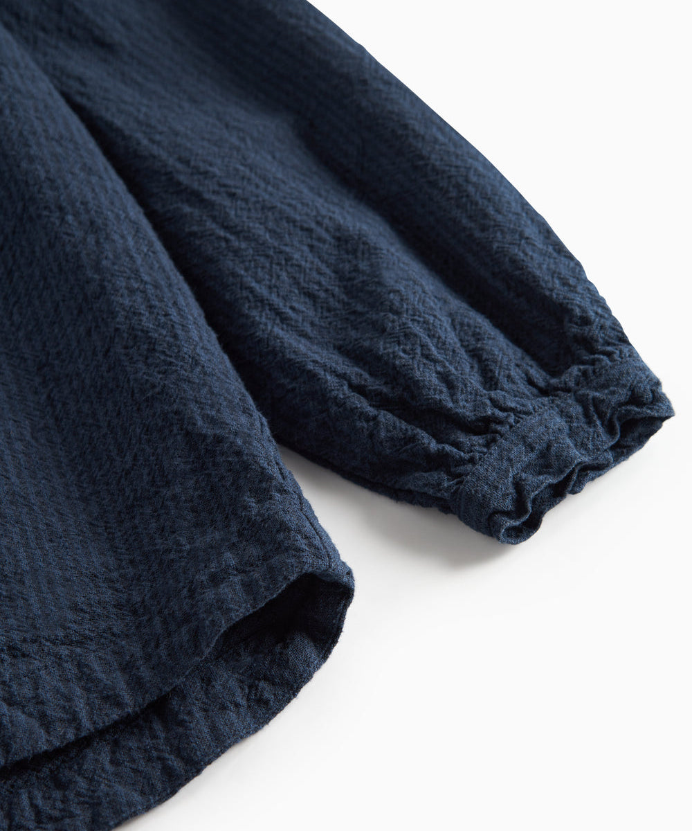 Detaljebillede af mørkeblå bluse med elastik ved ærmekant