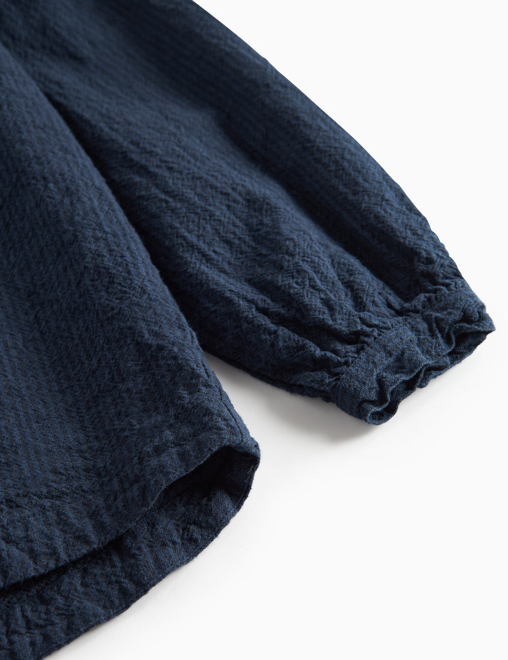 Detaljebillede af mørkeblå bluse med elastik ved ærmekant