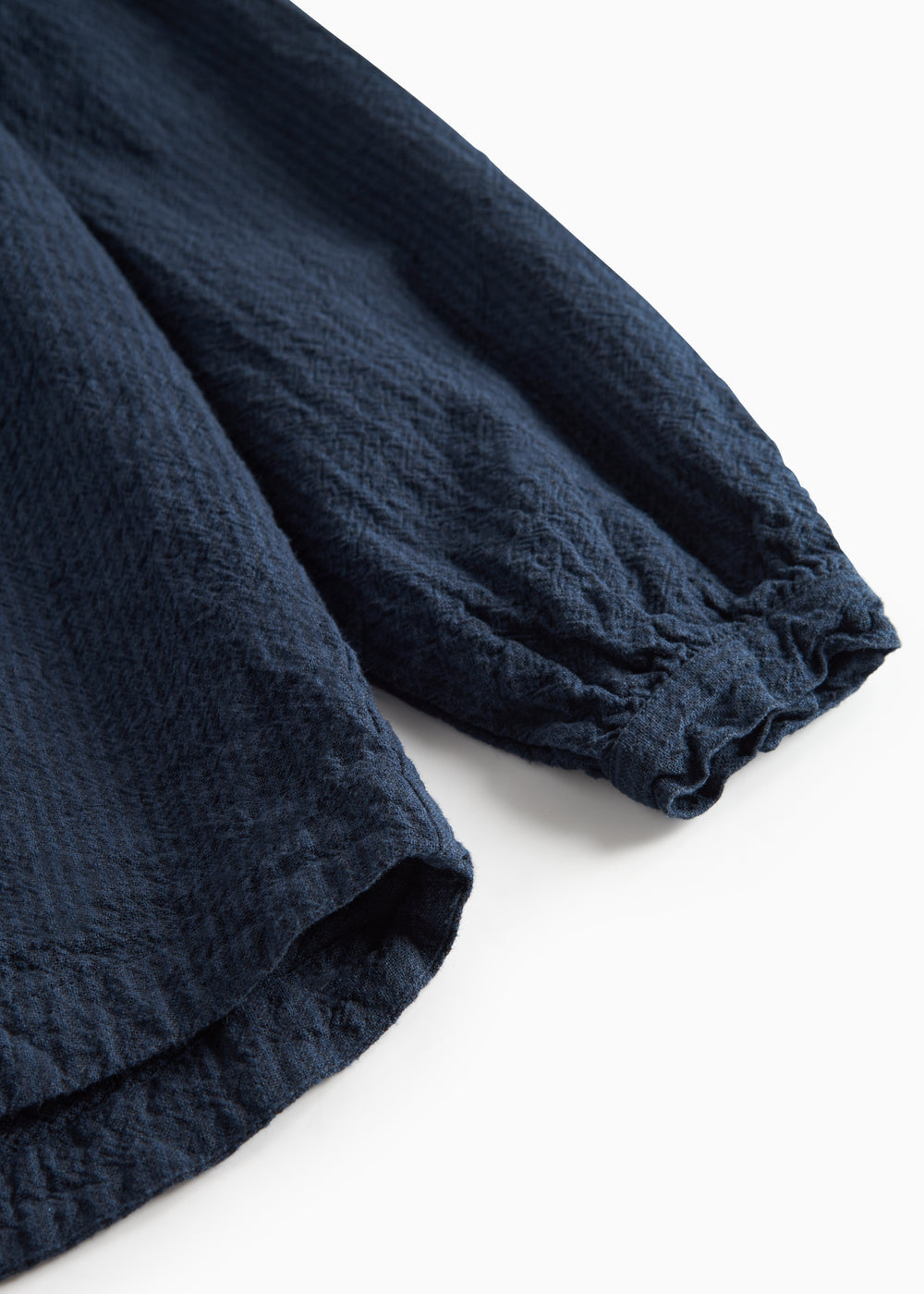 Detaljebillede af mørkeblå bluse med elastik ved ærmekant