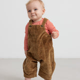 Baby iført rød og hvid stribet body og brune smækbukser