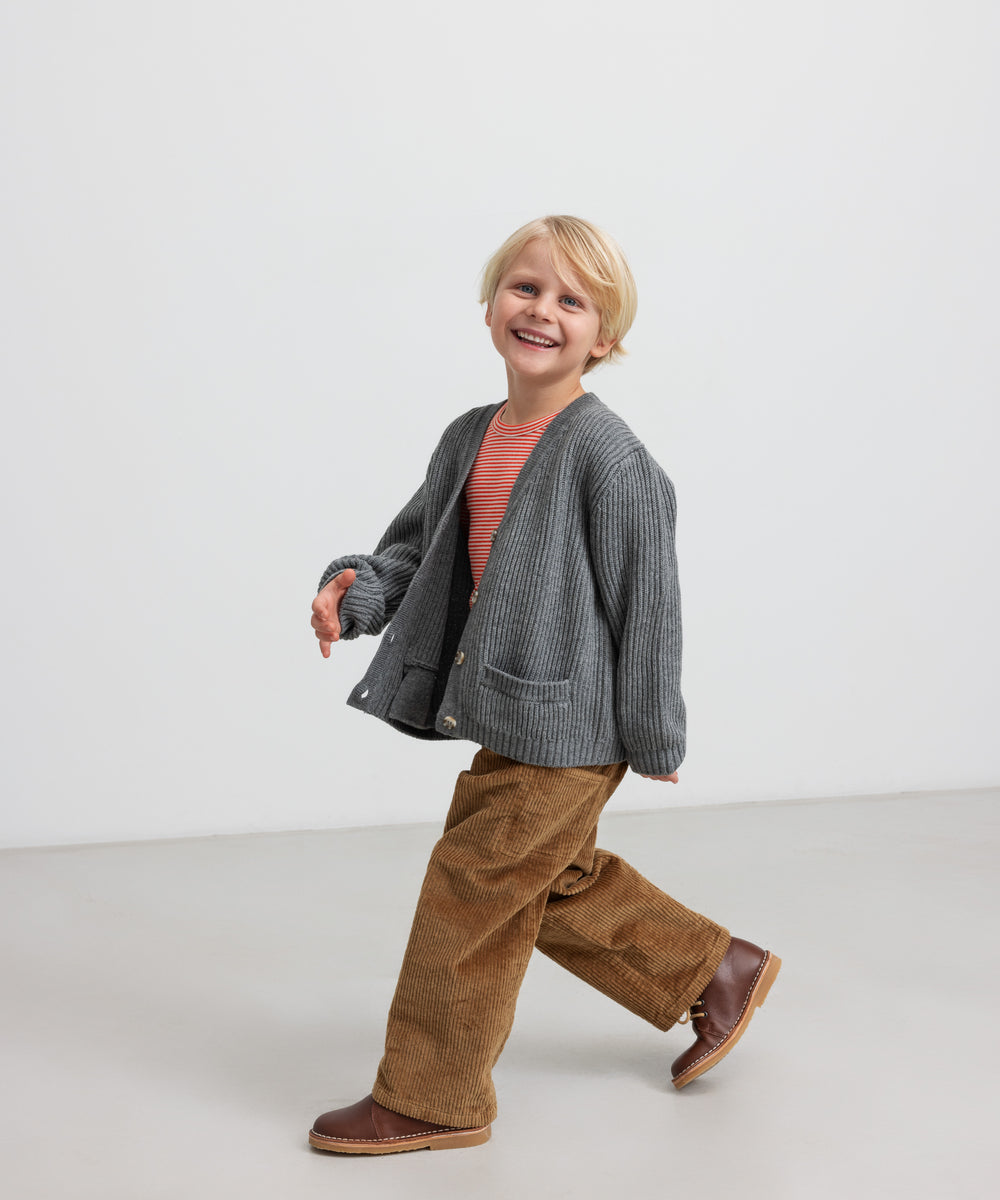 Dreng iført brune fløjlsbukser og grå cardigan