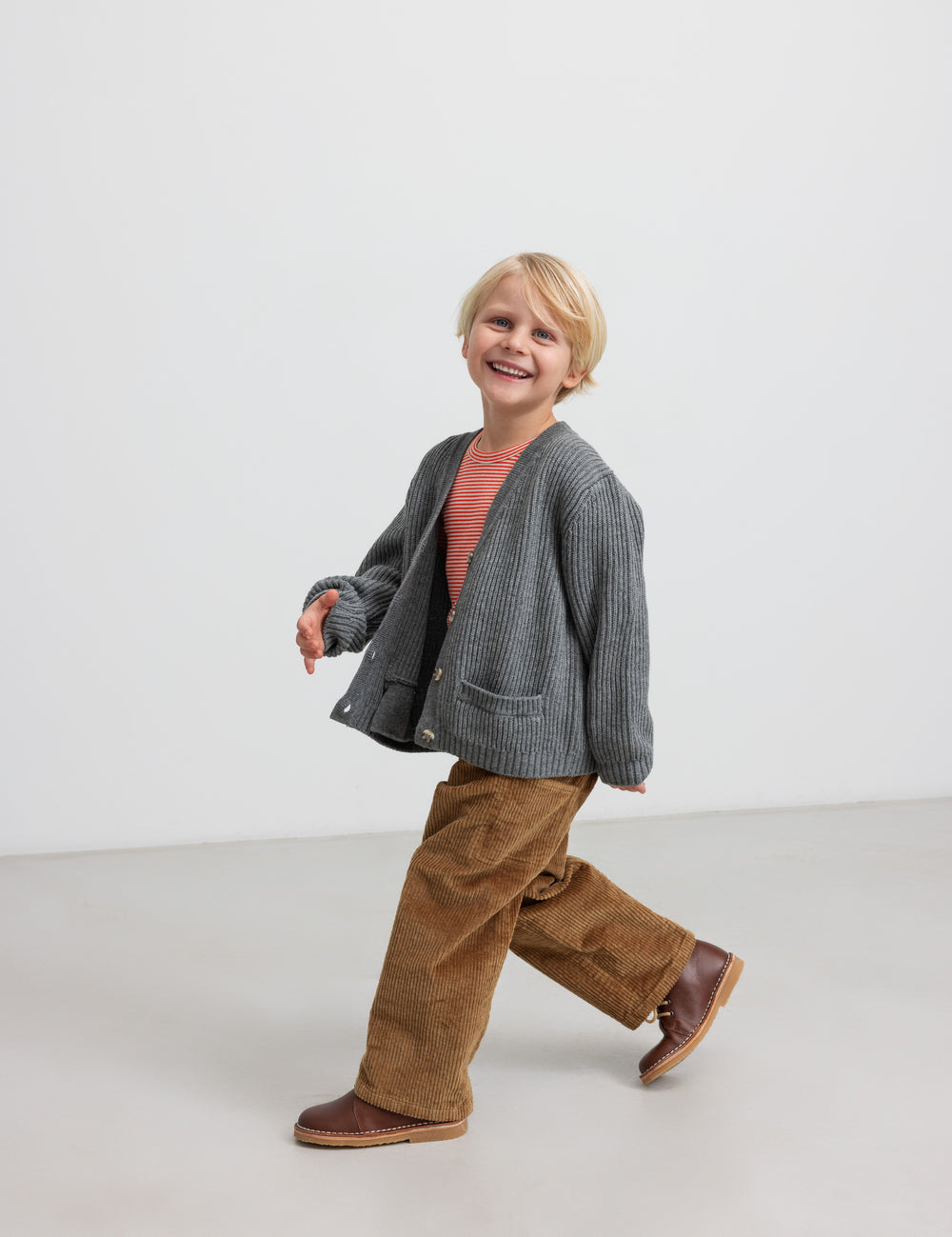 Dreng iført brune fløjlsbukser og grå cardigan