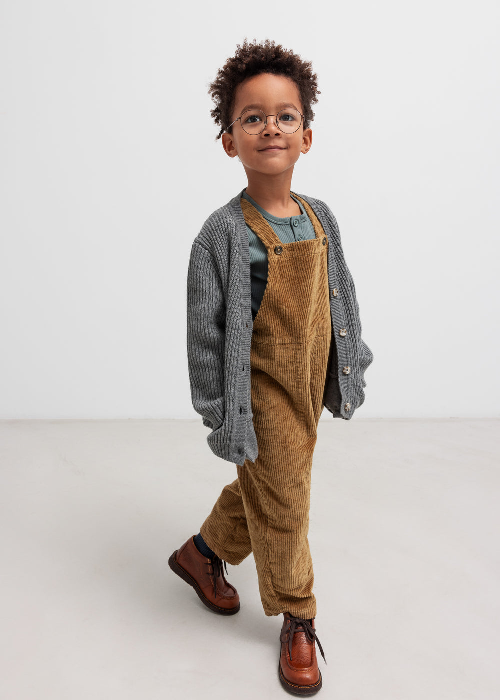 Dreng iført grøn ribstrikket bluse og brun overall