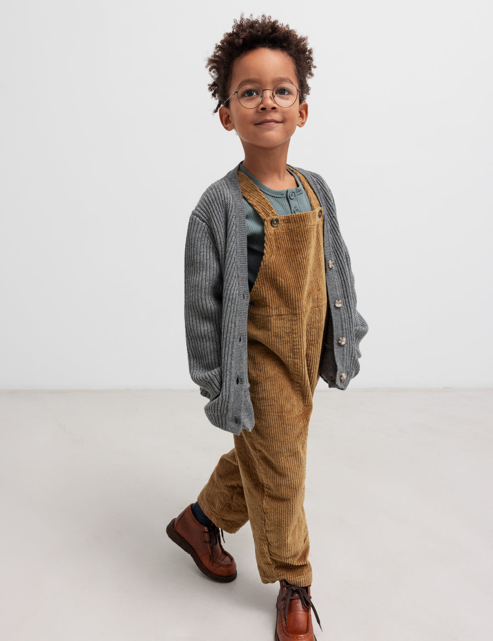 Boy wearing brown velvet jumpsuit and gray cardigan