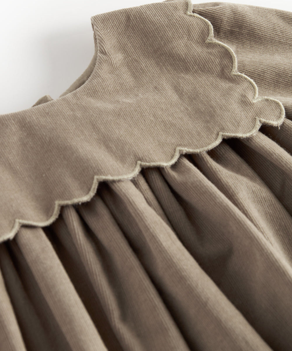 Beige babyfløjlskjole med lange ærmer, bølgekant og lommer til børn