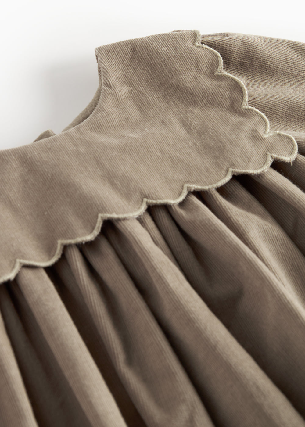 Beige babyfløjlskjole med lange ærmer, bølgekant og lommer til børn