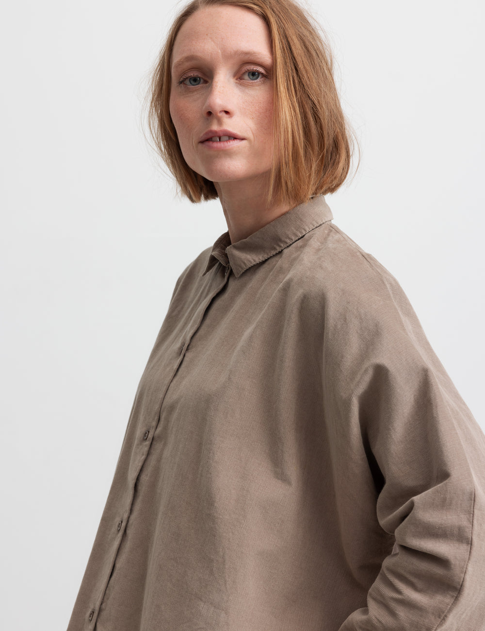 Kvinde iført beige skjorte med kinakrave