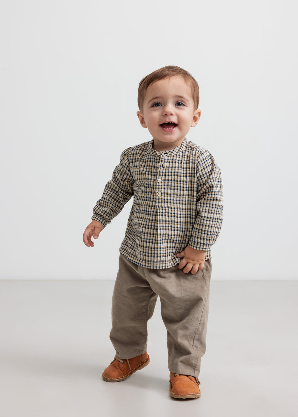 Baby iført beige babyfløjl­sbukser og bluse