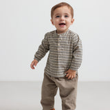 Baby iført beige babyfløjl­sbukser og bluse