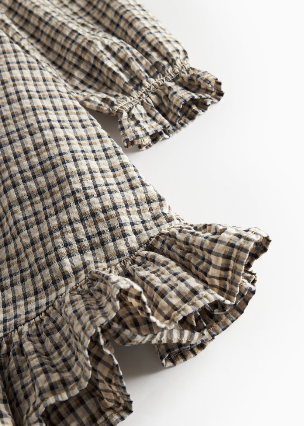 Detalje af flæser på brun ternet strikkjole