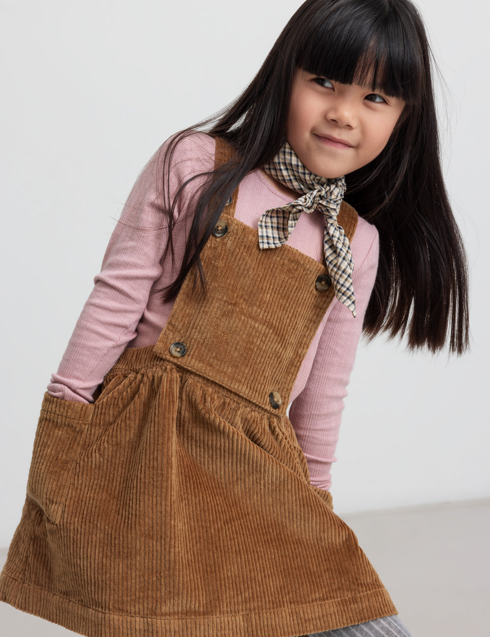 Girl wearing brown velvet strap dress and pink blouse
