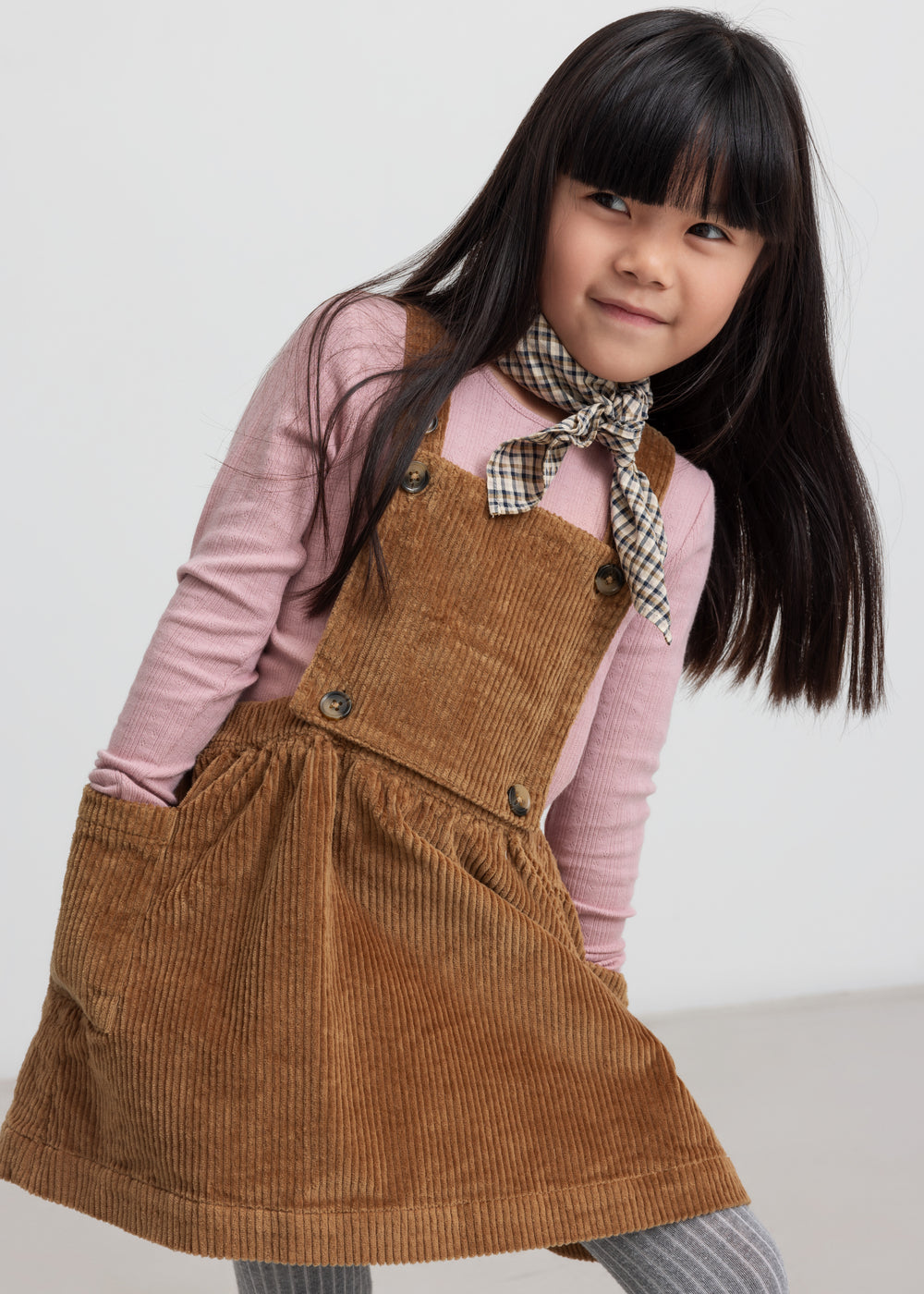 Pige iført brun fløjlssele­kjole og lyserød bluse