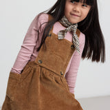 Pige iført brun fløjlssele­kjole og lyserød bluse