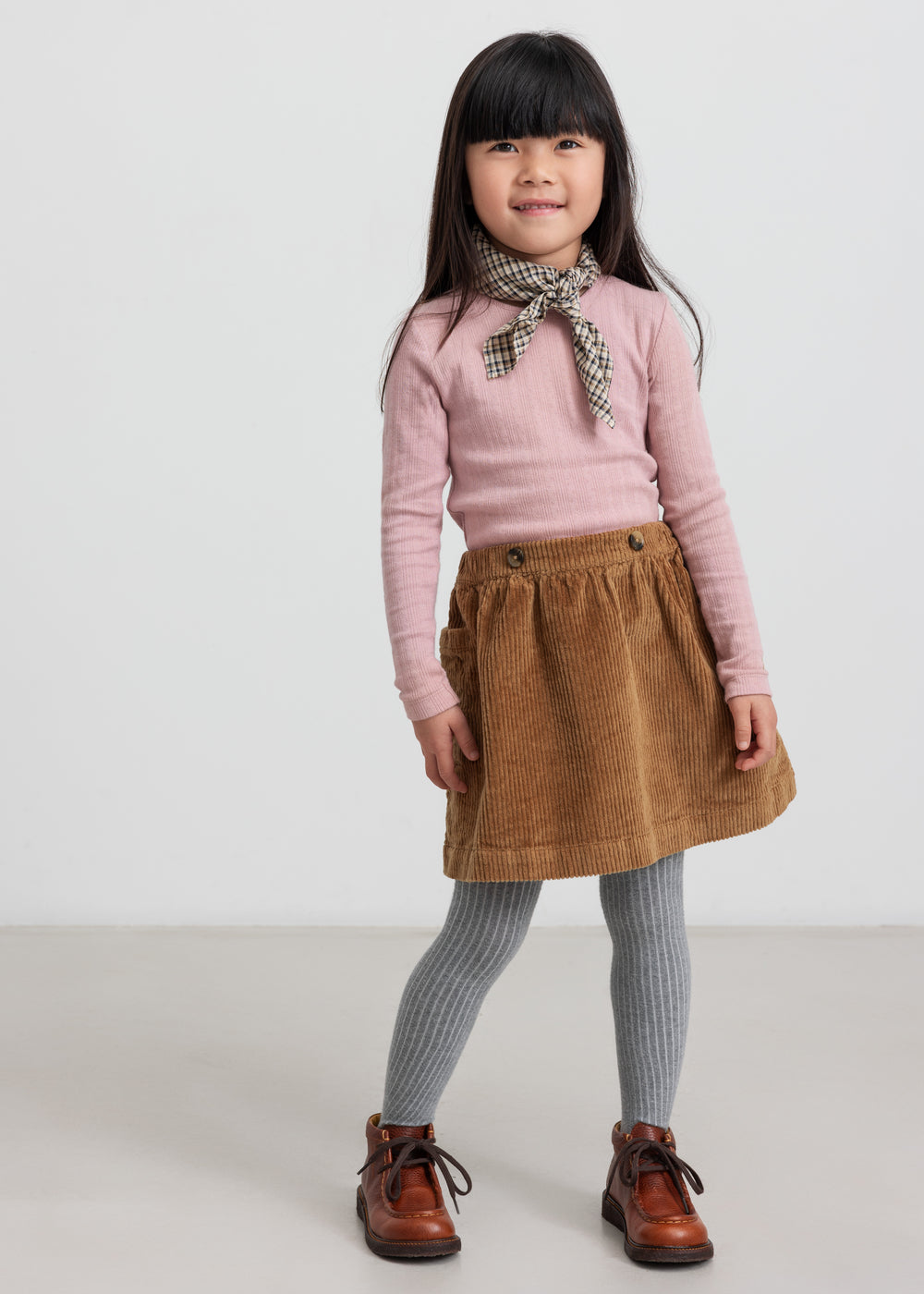 Pige iført brun fløjlnederdel og lyserød bluse