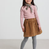 Pige iført rosa pointelle bluse og brun nederdel