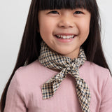 Pige med brun ternet tørklæde bundet om halsen og lyserød t-shirt