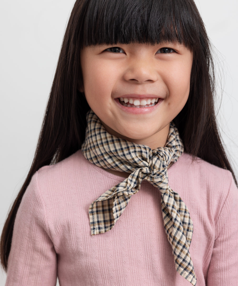 Børn iført rosa pointelle bluse og ternet tørklæde