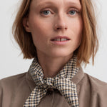 Kvinde iført brun ternet tørklæde bundet om halsen