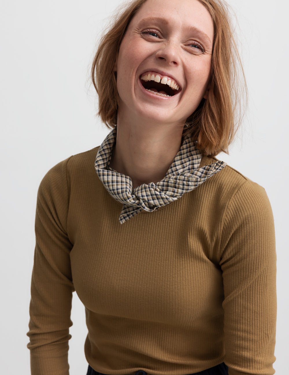 Kvinde iført brun ternet tørklæde bundet om halsen