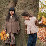 To piger i efterårstøj leger ved et træ ude i naturen