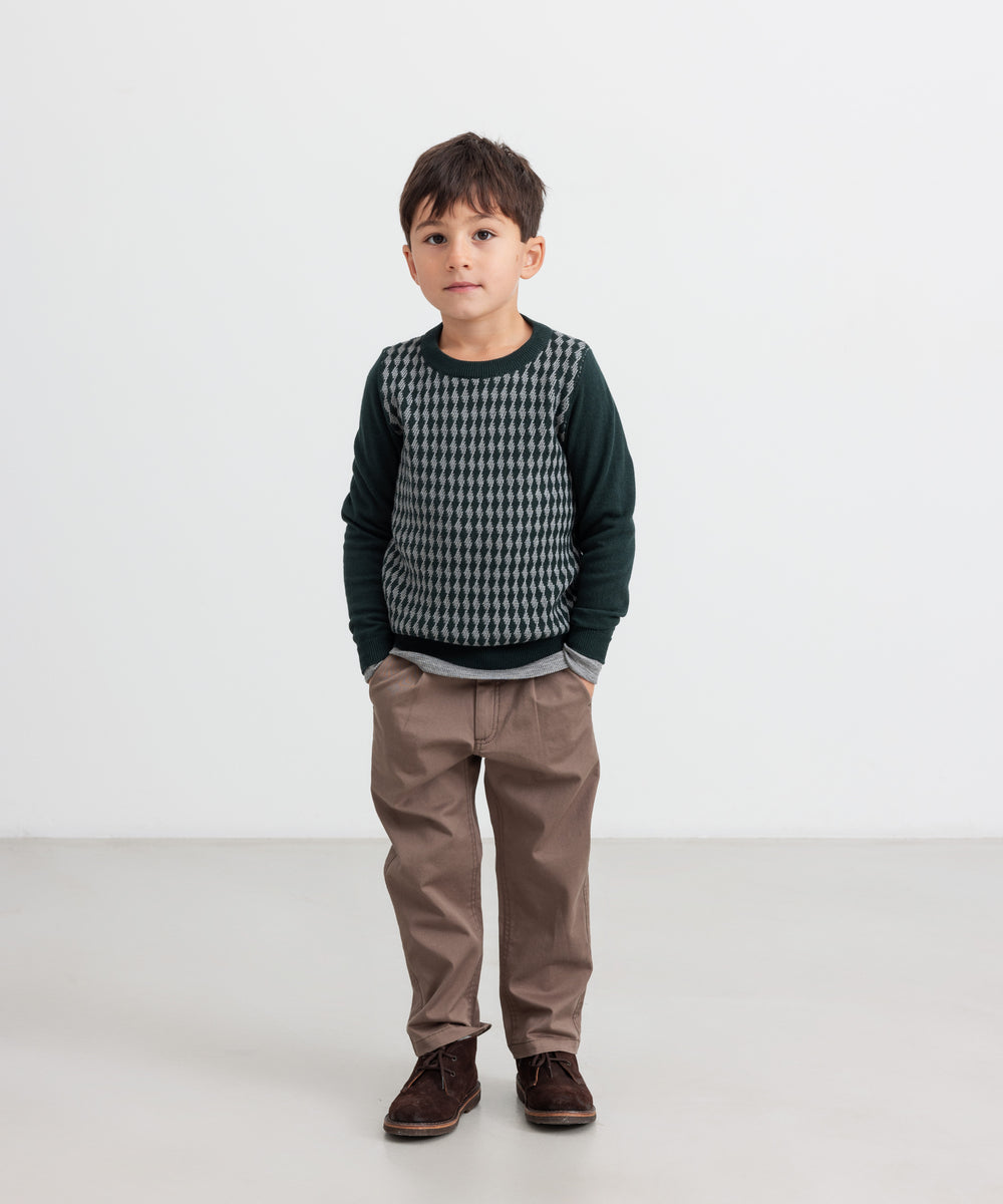 Dreng iført mørkegrøn strikket bluse med ternet mønster og brune bukser til børn