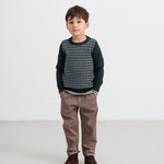 Dreng iført mørkegrøn strikket bluse med ternet mønster og brune bukser til børn