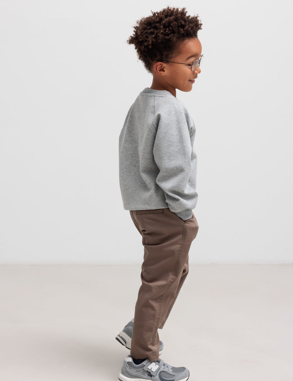 Barn iført en grå trøje og brune bukser