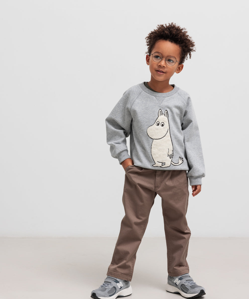 Dreng iført grå Moomin trøje og kaki bukser a