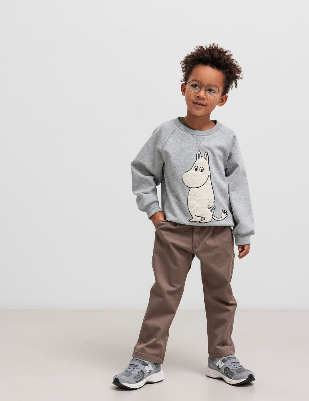 Dreng iført grå Moomin trøje og kaki bukser.