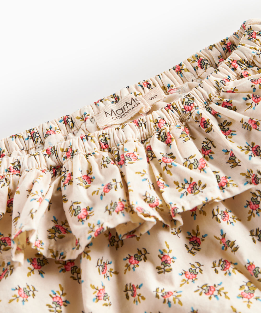 Detaljebillede af bloomers med blomstermønster og flæser