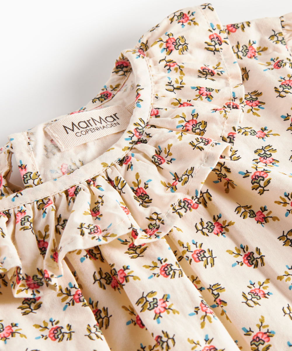 Detaljebillede af bluse med blomstermønster og flæsedetalje