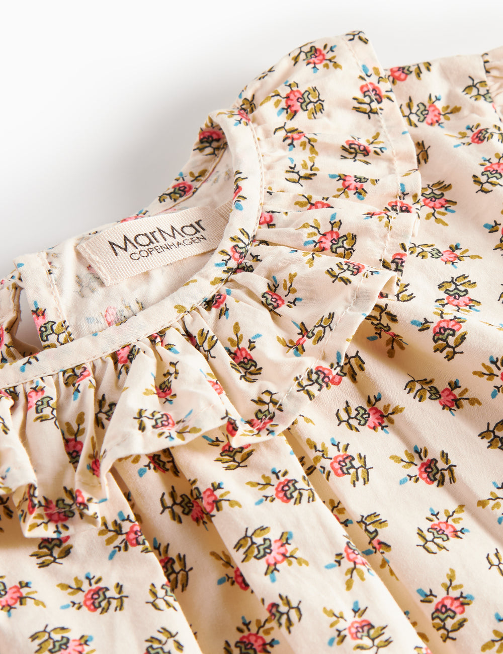 Detaljebillede af bluse med blomstermønster og flæsedetalje