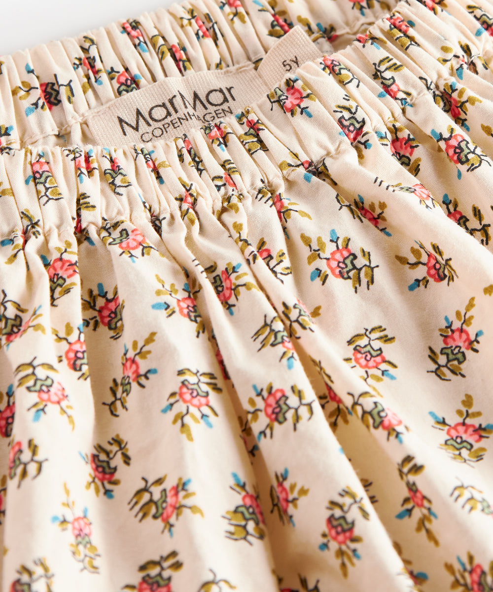 Nærbillede af stof med blomstermønster og flæsekant på nederdel