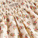 Nærbillede af stof med blomstermønster og flæsekant på nederdel